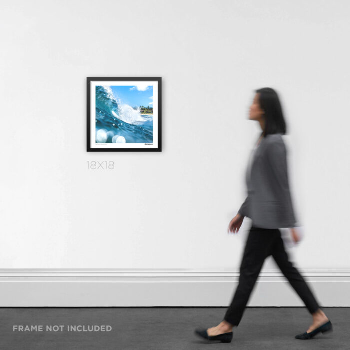 18x18 square framed coastal wall art mockup showcasing a clean, hollow turquoise wave breaking over a shallow reef in Hawaii, styled on a gallery wall for scale.