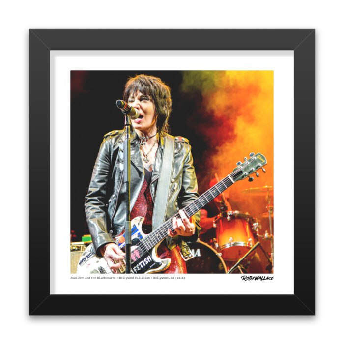 Close-up view of a 12x12 square framed music documentary print of trailblazer Joan Jett rip-roaring through a set of classics with her custom guitar and signature FETISH strap text showing.