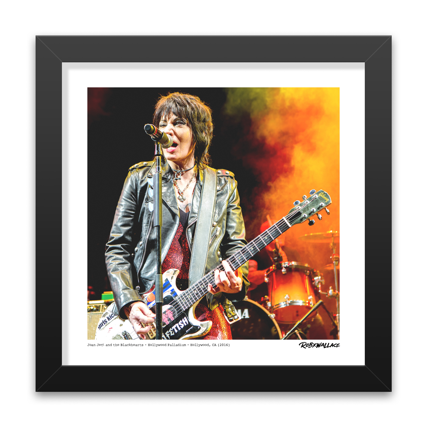 Close-up view of a 12x12 square framed music documentary print of trailblazer Joan Jett rip-roaring through a set of classics with her custom guitar and signature FETISH strap text showing.